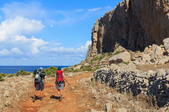 Two unidentified men walk the path to the rocks in Sicily