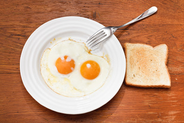 breakfast with two fried eggs in white plate