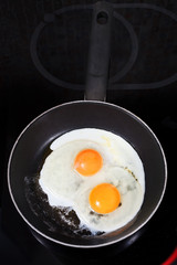 two fried eggs in hot frying pan