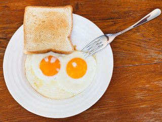 breakfast with two fried eggs in white plate