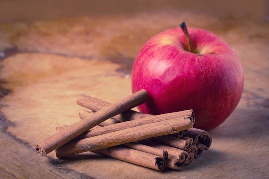 Cinnamon and apple on wooden background.