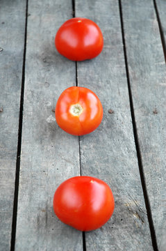 Three whole tomatoes on wooden background