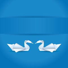 Origami swans on blue background