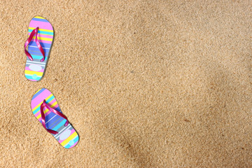Fototapeta na wymiar flip flops on beach sand. room for text.