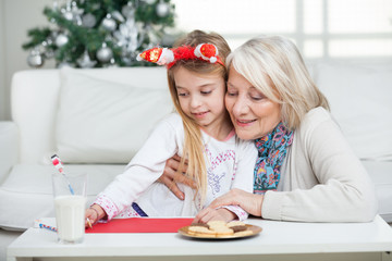 Grandmother Assisting Girl In Writing Letter To Santa Claus