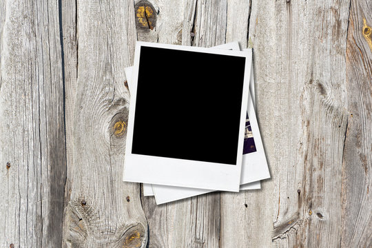 Blank photo frames on old wooden background.