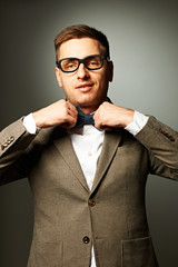 Confident nerd in eyeglasses adjusting his bow-tie