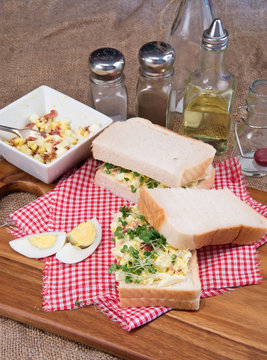 Fresh egg and bacn on white sandwich in rustic kitchen setting