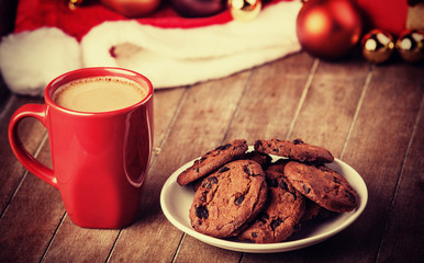 Cookies and cup of coffee with christmas gifts at background