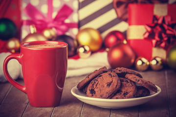 Cookies and cup of coffee with christmas gifts at background