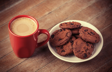 Cookies and cup of coffee with christmas gifts at background