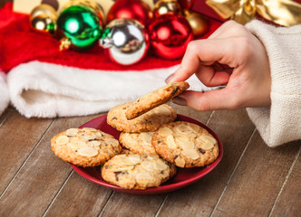 Female hand holding cookie at christmas gift background