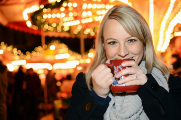 Frau trinkt Glühwein auf Weihnachtsmarkt