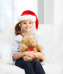 smiling girl in santa helper hat with teddy bear