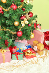 Decorated Christmas tree with gifts on green wall background