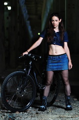 Fototapeta na wymiar A girl stands near an abandoned indoor bike
