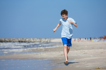 Fototapeta na wymiar Teenage boy running, jumping on beach