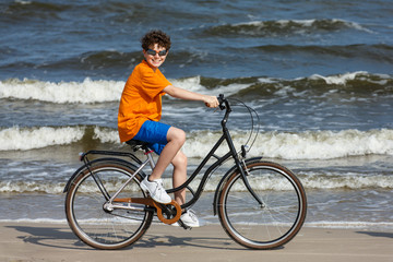 Teenage boy biking on beach