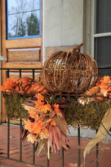 Metal pumpkin and colorful leaves on railing