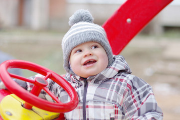 happy baby age 1 year driving car on playground