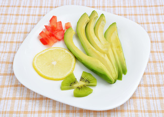 Avocado and lemon segments on a white plate