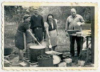 CIRCA 1960: A group of people preparing food on fire in big pots