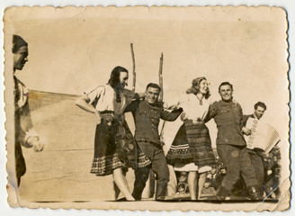CIRCA 1945: Celebration, women and men (young soldiers) dancing.