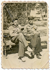 Fototapeta na wymiar CIRCA 1935: Young men in uniform sitting on a park bench