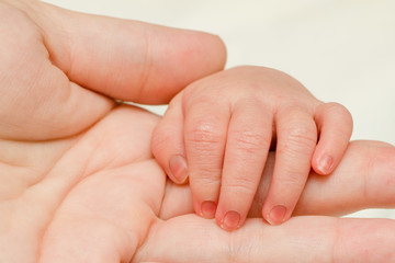 Close up of infant hand on top of mother's hand