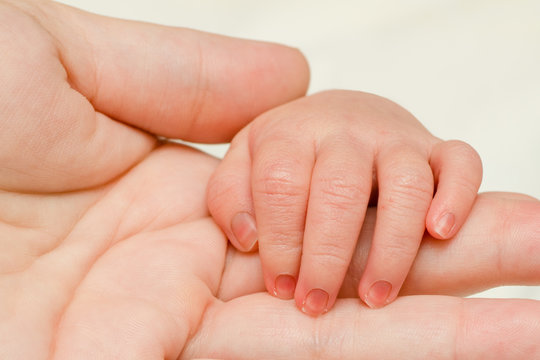 Close up of infant hand on top of mother's hand