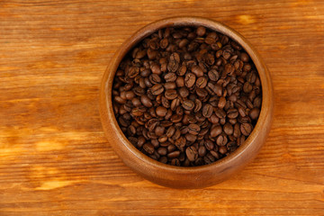 Coffee beans in wooden bowl on wooden background