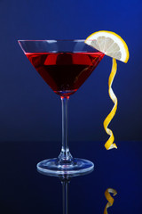 Red cocktail in martini glass on dark blue background