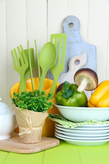 Plastic kitchen utensils in cup on wooden table