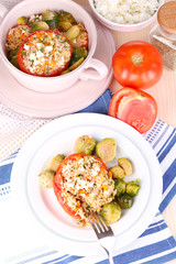 Stuffed tomatoes in plate and pan on wooden table close-up