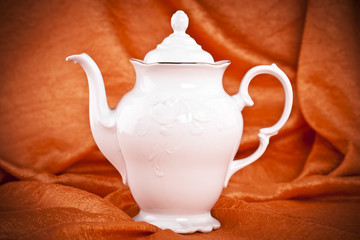 teapot isolated on orange fabric  background