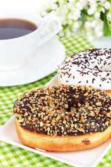 Sweet donuts with cup of tea on table close-up