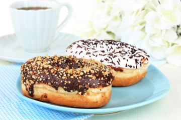Sweet donuts with cup of tea on table close-up