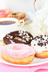 Sweet donuts with cup of tea on table on light background