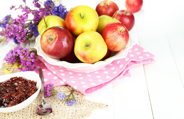 Juicy apples on plate on white wooden table