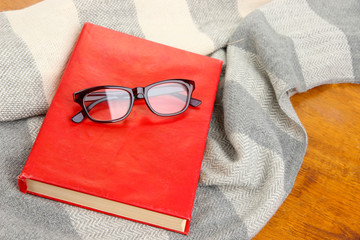 Composition with old book, eye glasses and plaid