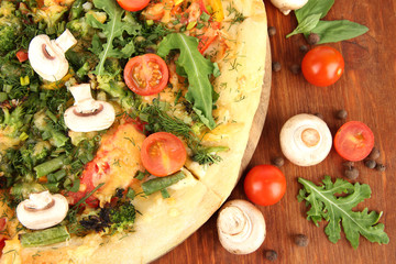 Tasty vegetarian pizza and vegetables on wooden table