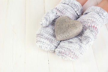 Fototapeta na wymiar Female hands in mittens with heart on wooden background