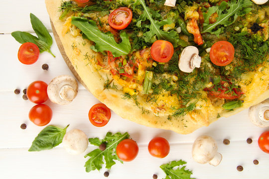 Tasty vegetarian pizza and vegetables on wooden table