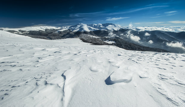 Winter alpine scenery with snow dunes and frozen snow