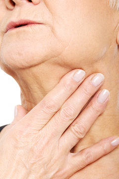 Close up on older woman's hand holding neck.