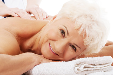 An elderly woman is having a massage at spa resort.