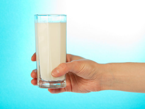 The female hand holds a full glass of milk