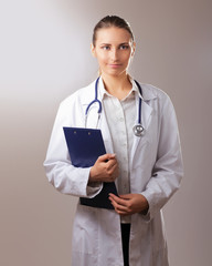 A female doctor with a folder , isolated on grey background.