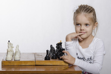 Девочка с хитрым взглядом, сидит за шахматной доской