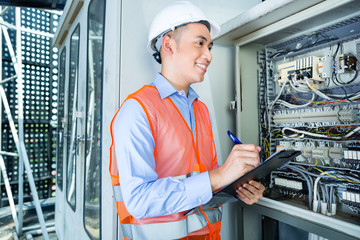 Asian Electrician at panel on construction site © Kzenon